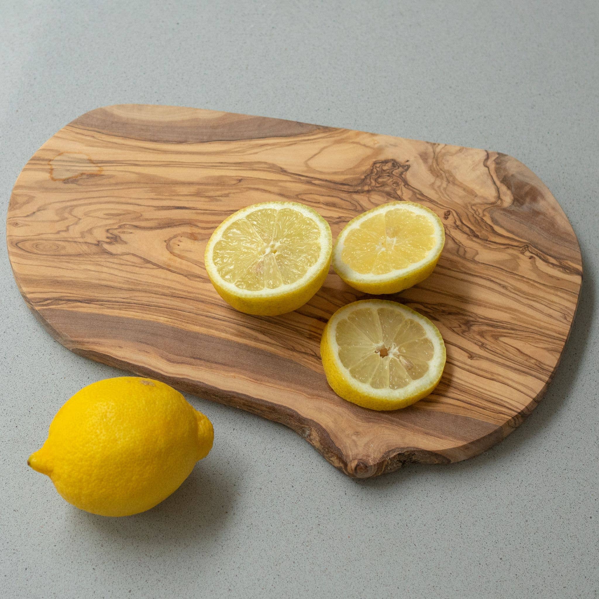 Wooden cutting board with sliced lemons on a gray background