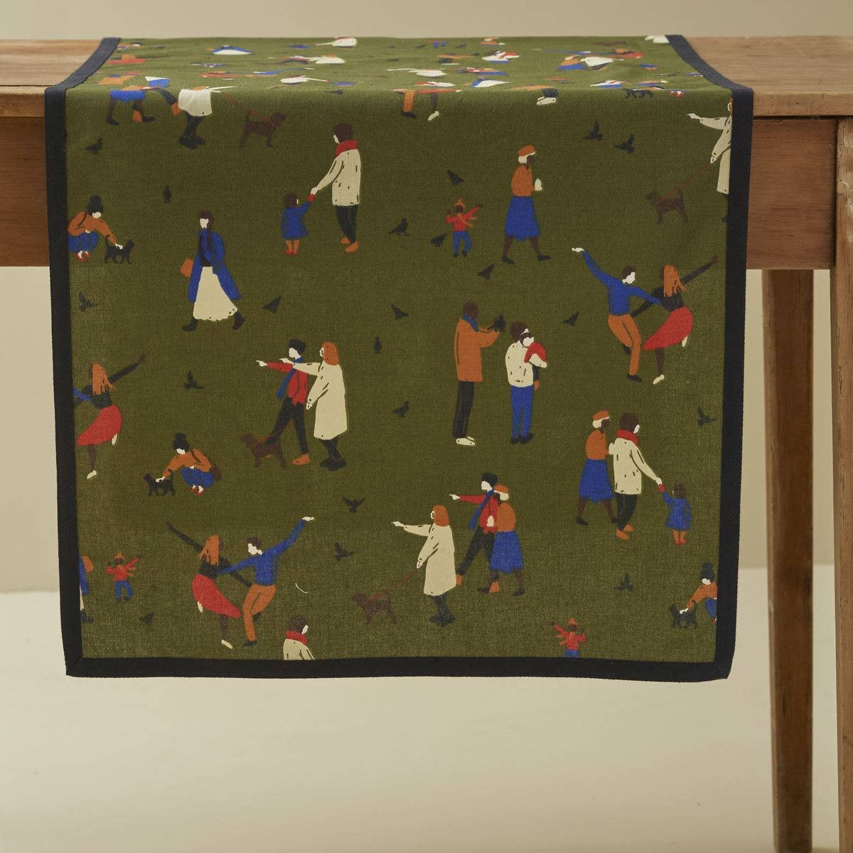 Green table runner with park scene design on a wooden table.