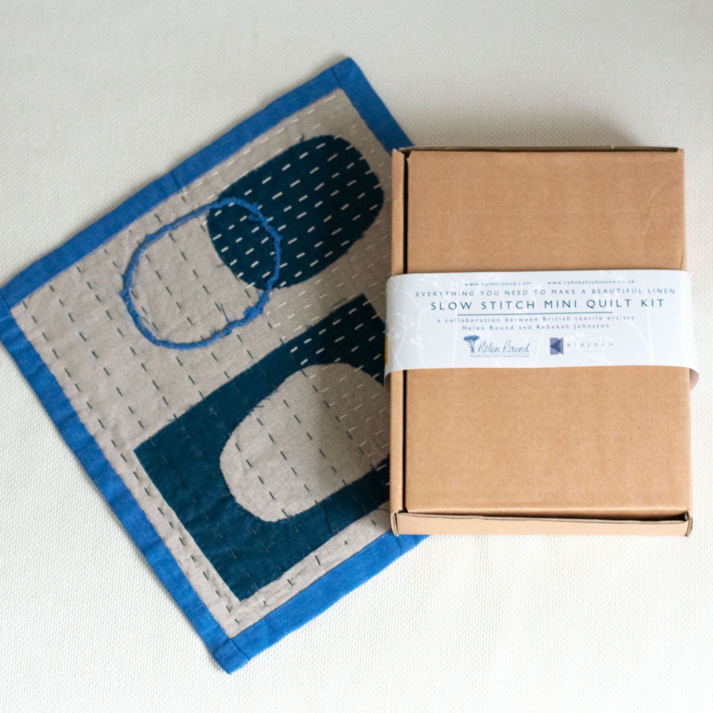 Mini quilt kit with a cardboard box on a light background