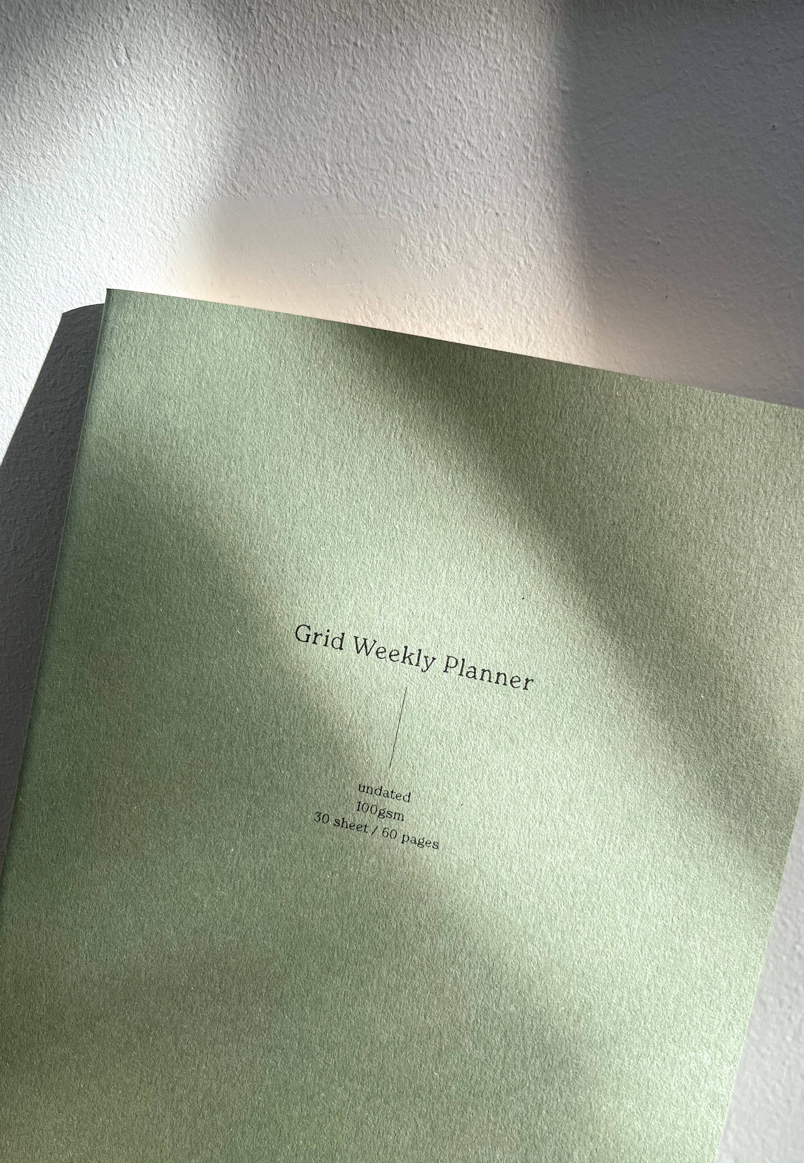 Green planner with 'Grid Weekly Planner' text on a white surface