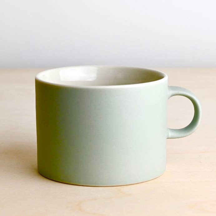 Green mug on a wooden surface with a light gray background