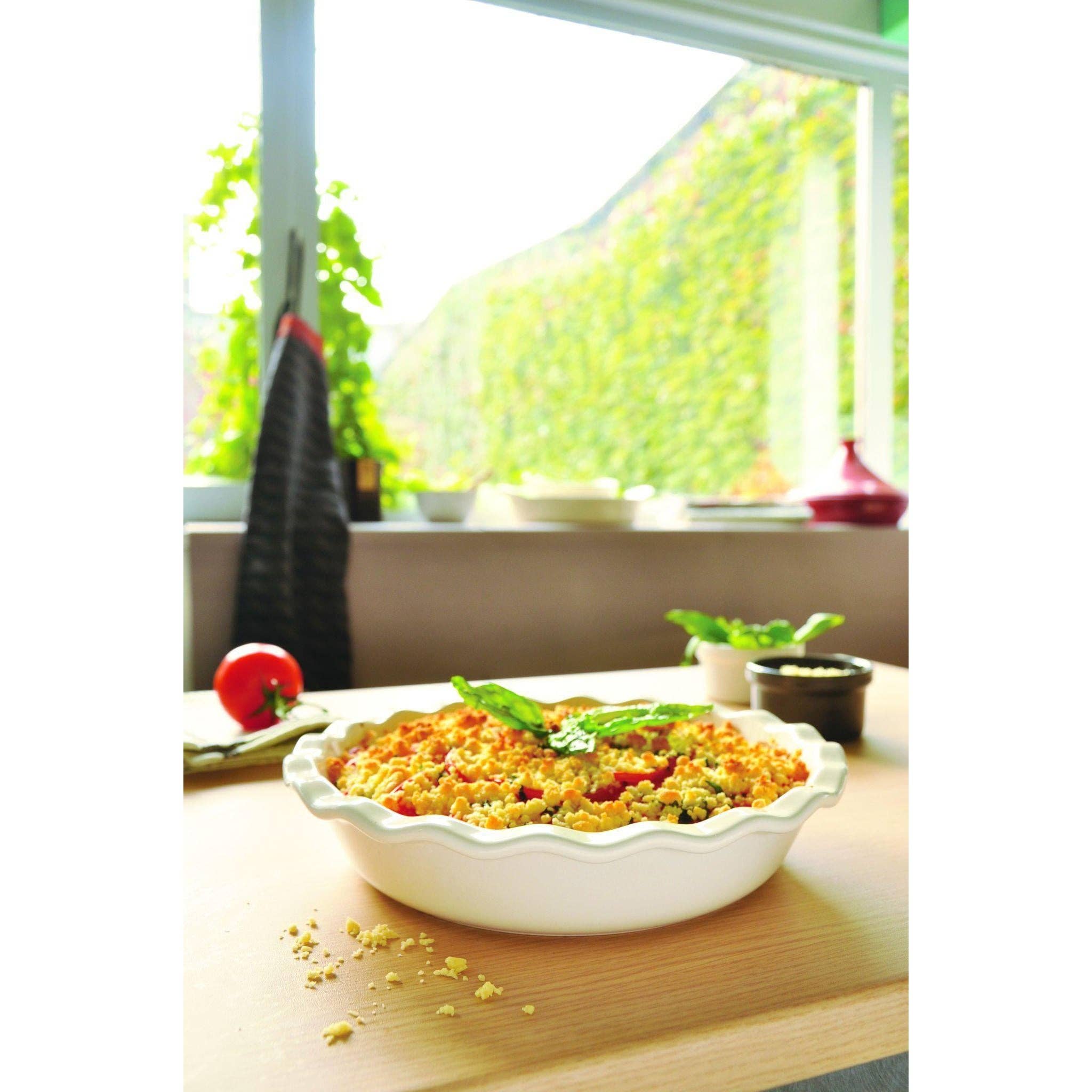 Casserole dish with a colorful dish on a table with a window in the background