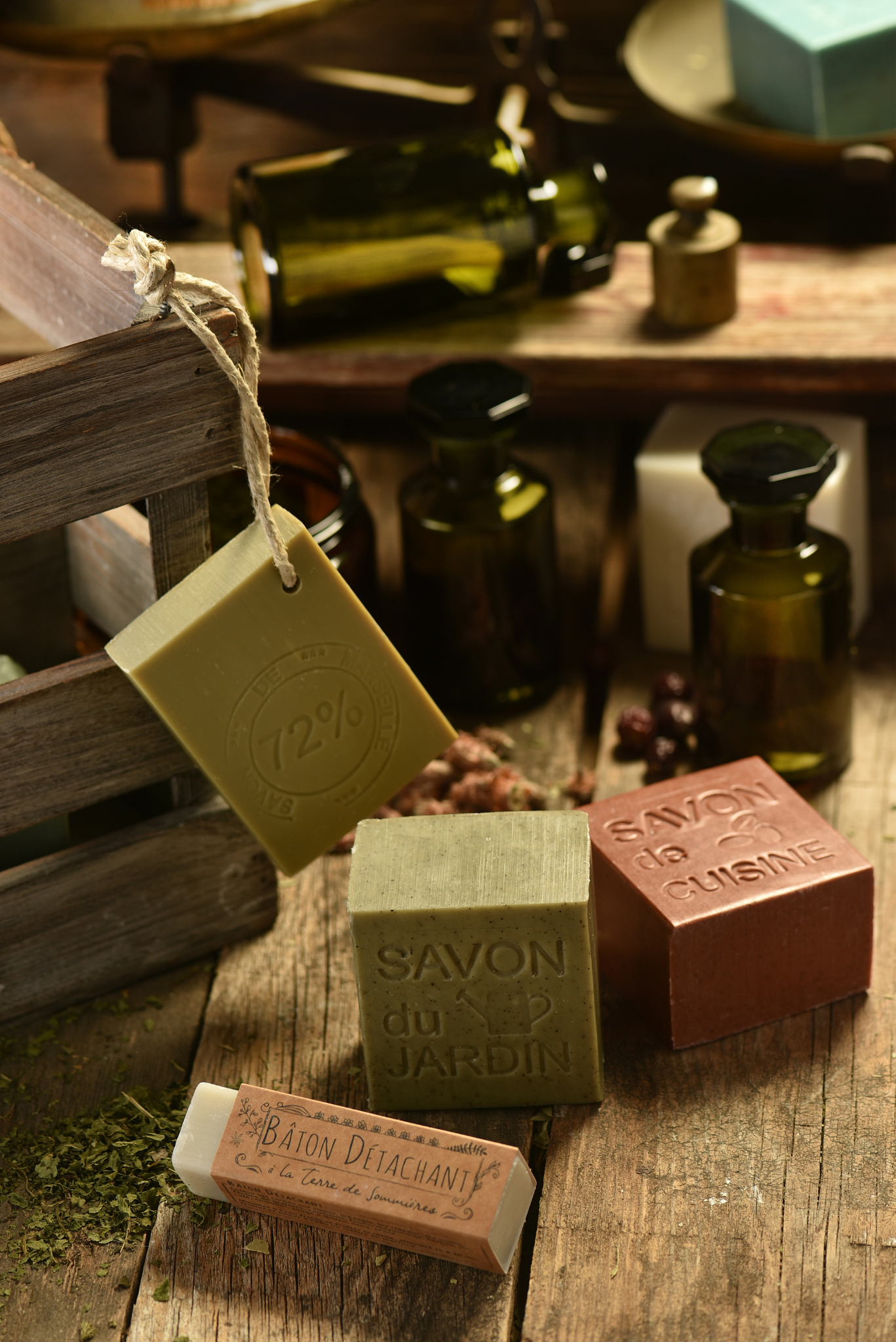 Various soaps on a wooden surface with bottles in the background