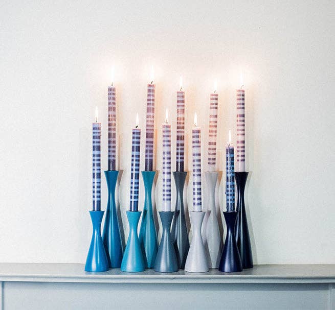 Set of candle holders with candles on a white surface