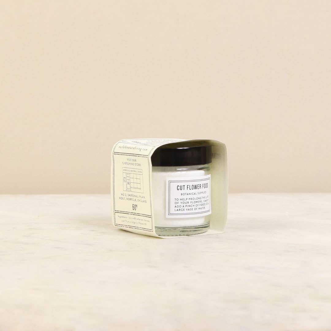 Cut flower food in a glass jar with a black lid on a beige background
