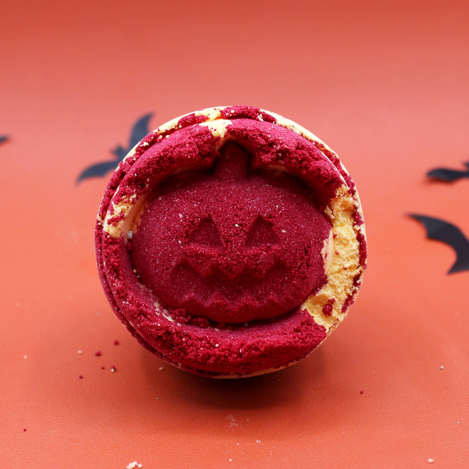 Halloween-themed bath additive with red center and pumpkin face on orange background