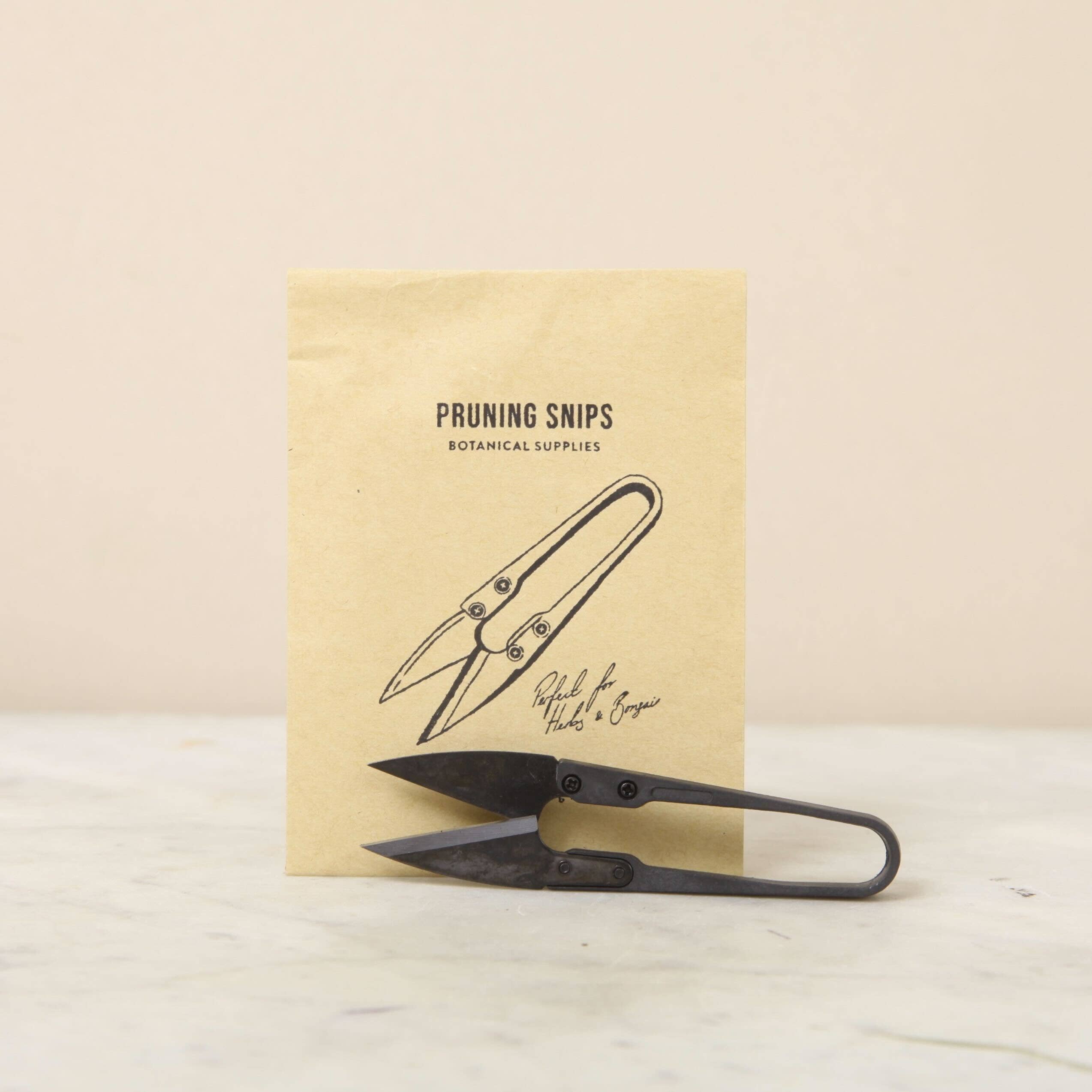 Pruning shears with a branded paper bag on a light background