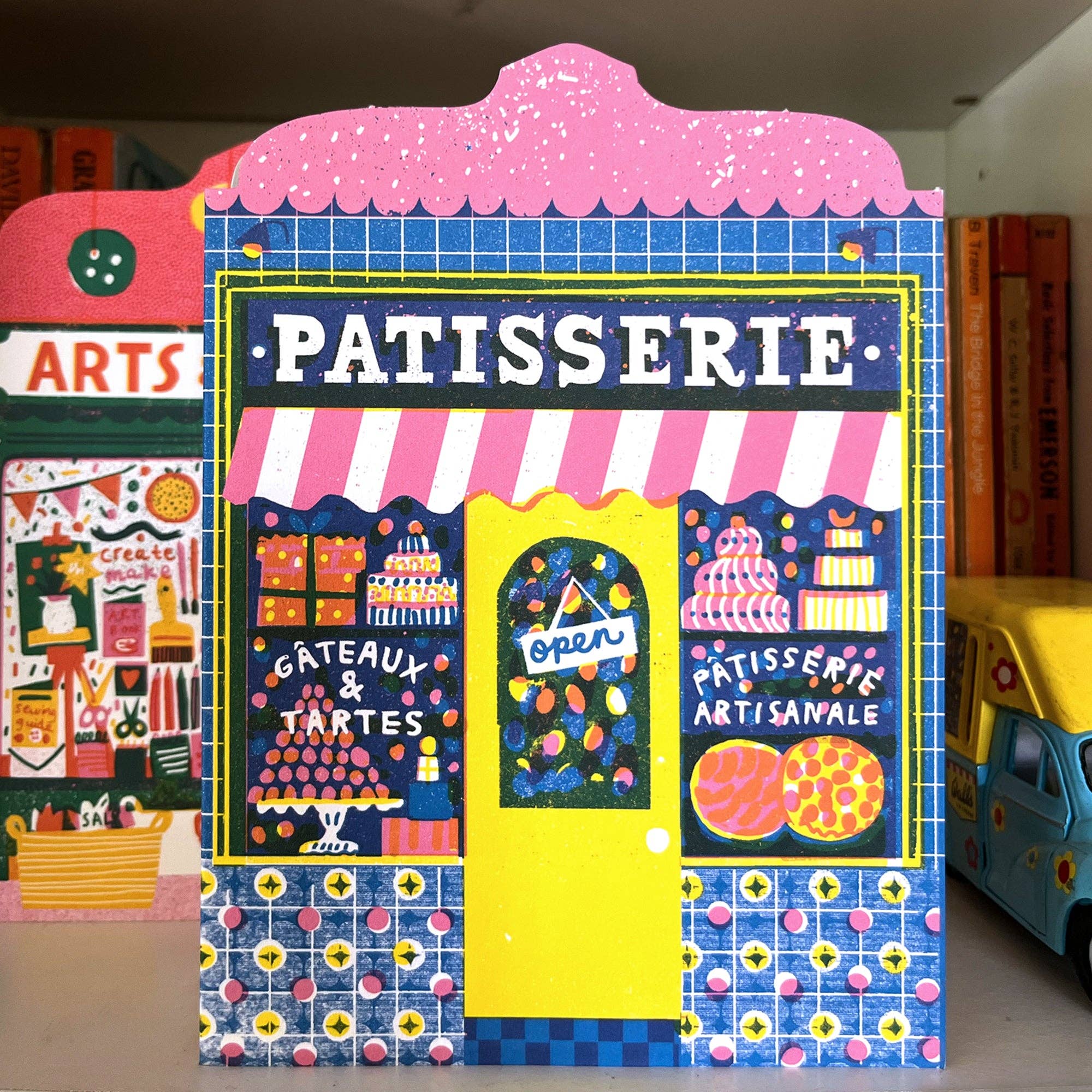 Colorful display of a 'Patisserie' themed stand with a pink roof and blue walls.
