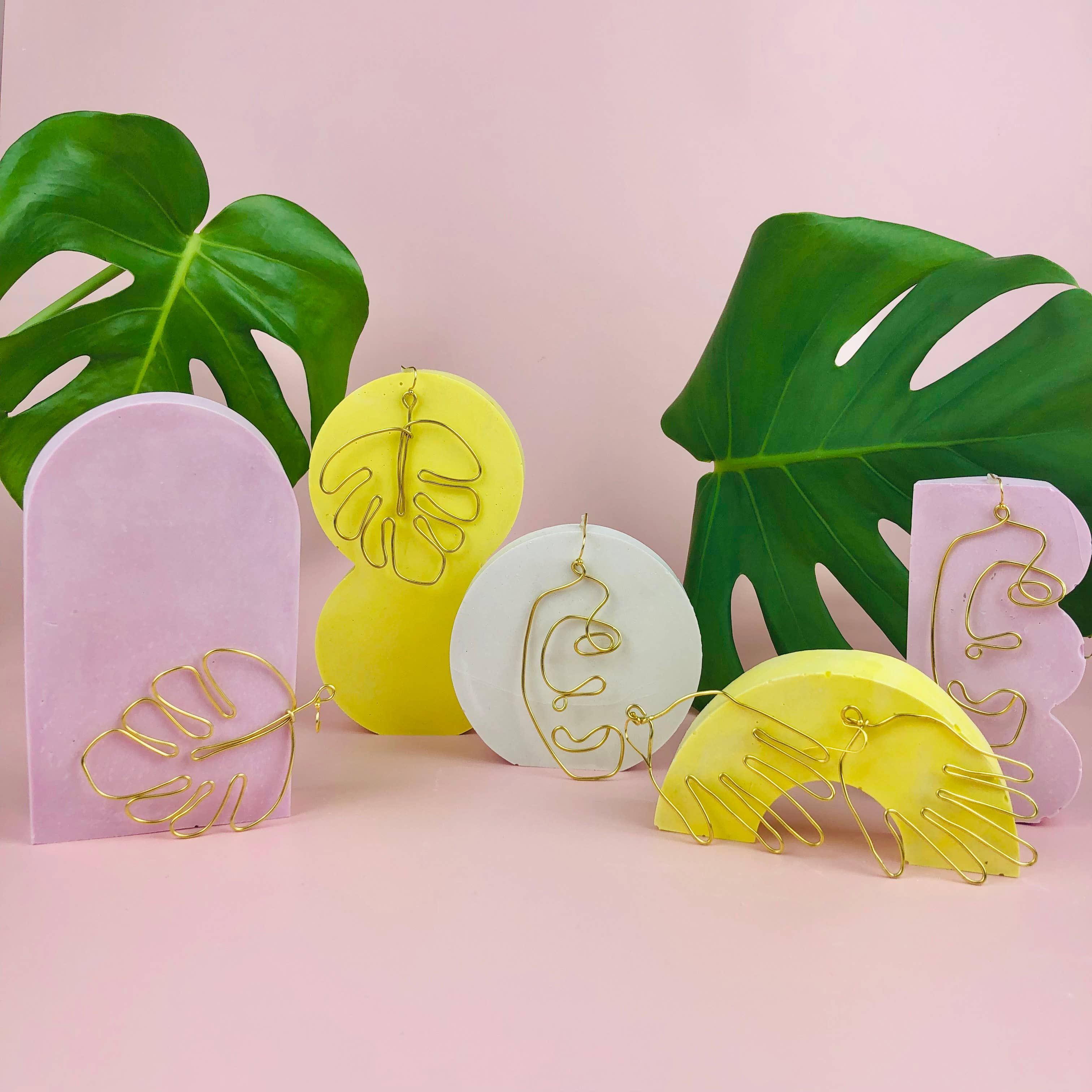 earrings with leaf designs on a pink background