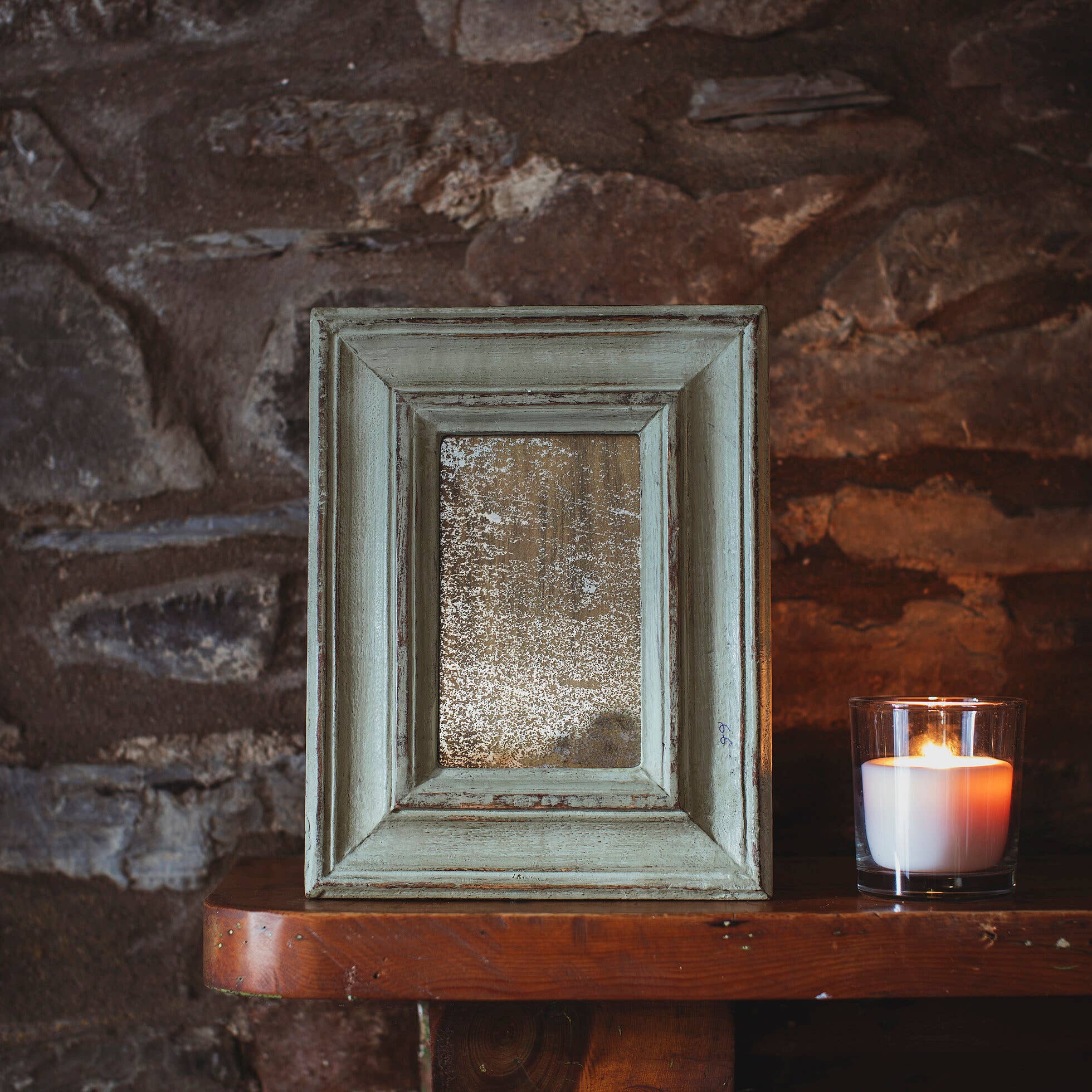 Vintage mirror in a rustic setting with a candle