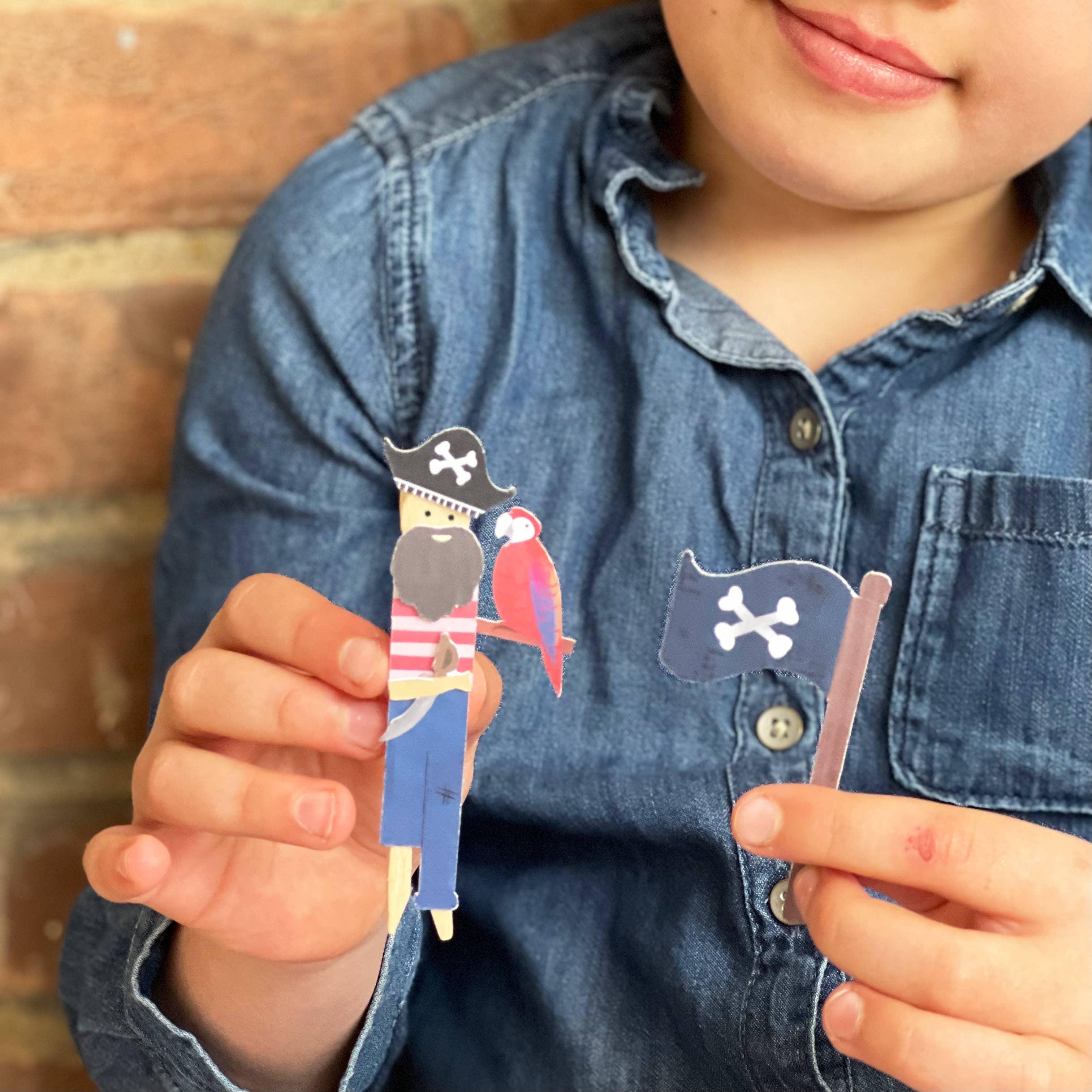 Child holding a pirate-themed paper toy with a parrot against a wooden background