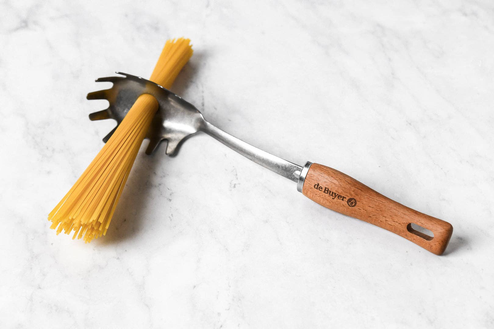 Spaghetti noodles with a pasta fork on a white surface