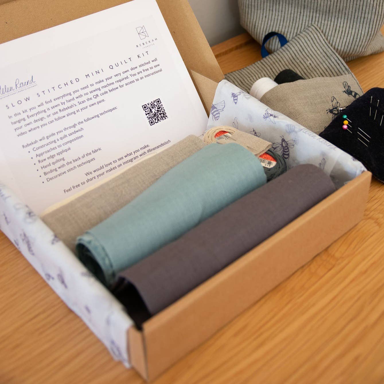 Box containing fabric rolls and a paper with text on a wooden surface