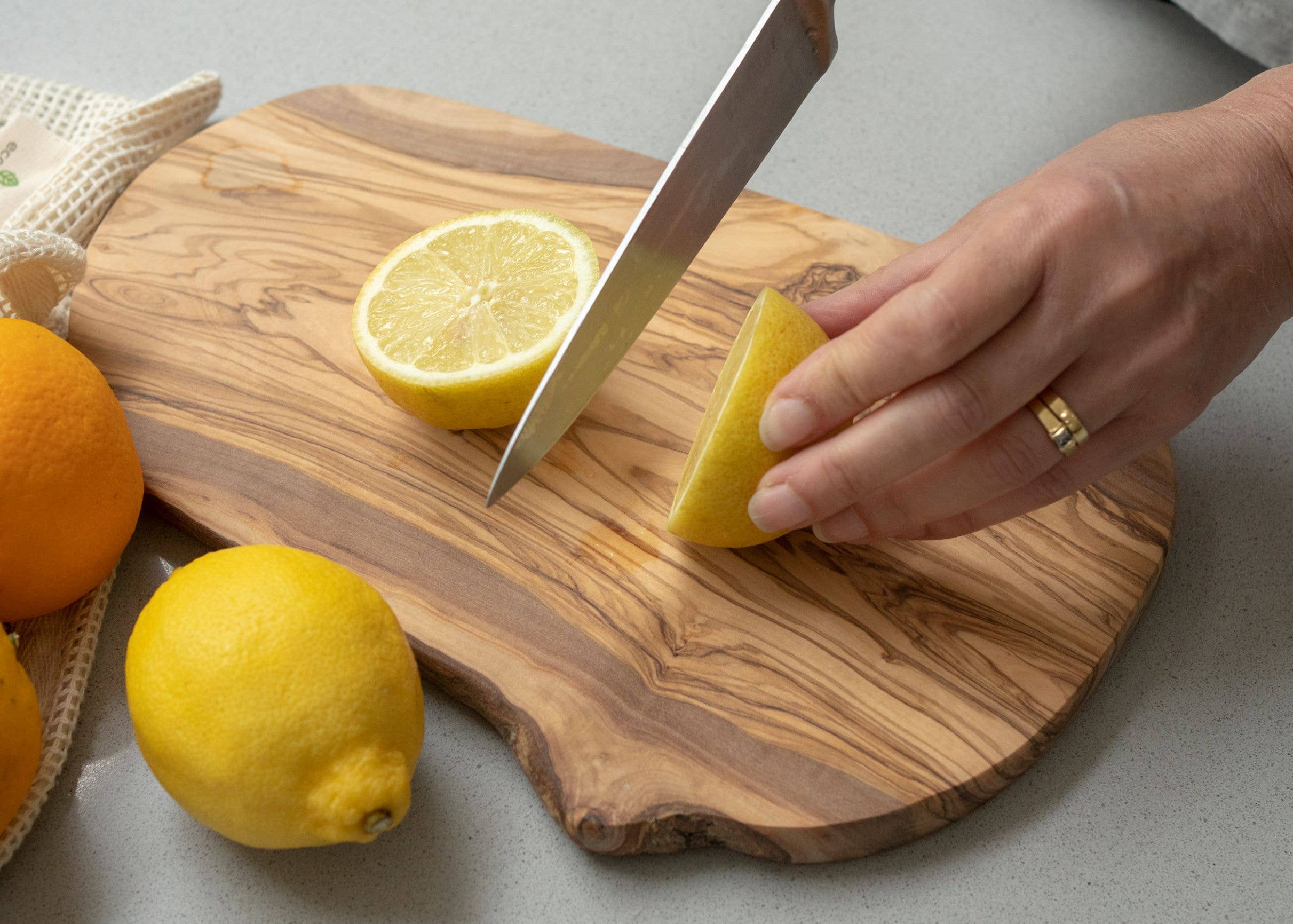Person cutting lemons on a wooden cutting board with a knife.