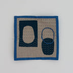 Square quilt with blue border featuring abstract shapes on a light gray background