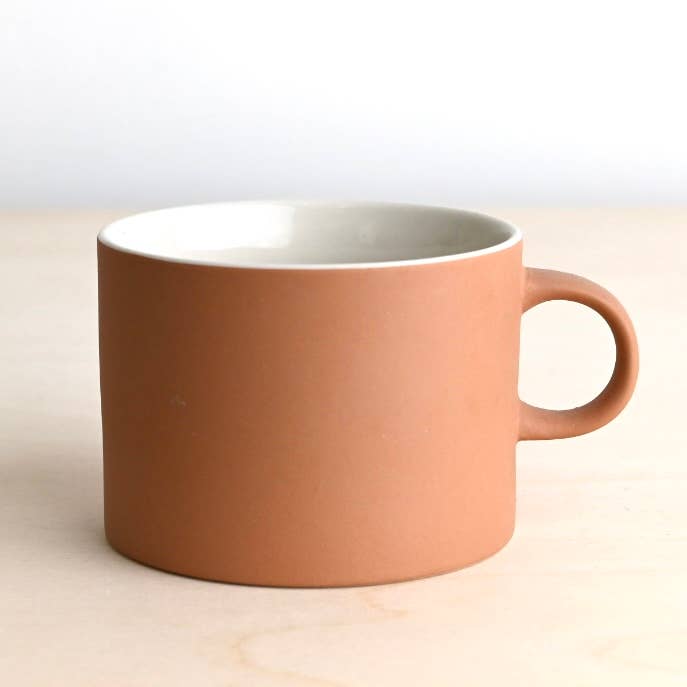 Ceramic mug with a handle on a light wooden surface