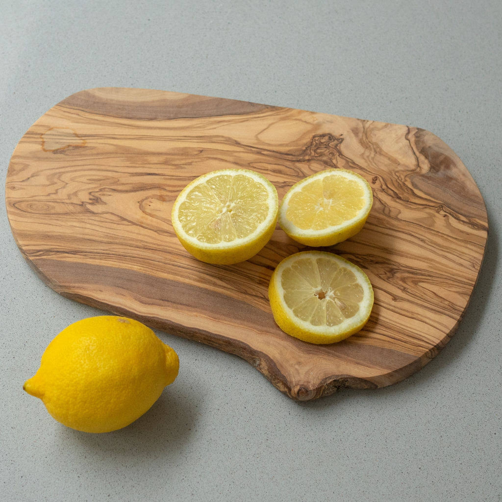 Wooden cutting board with sliced lemons on a gray background