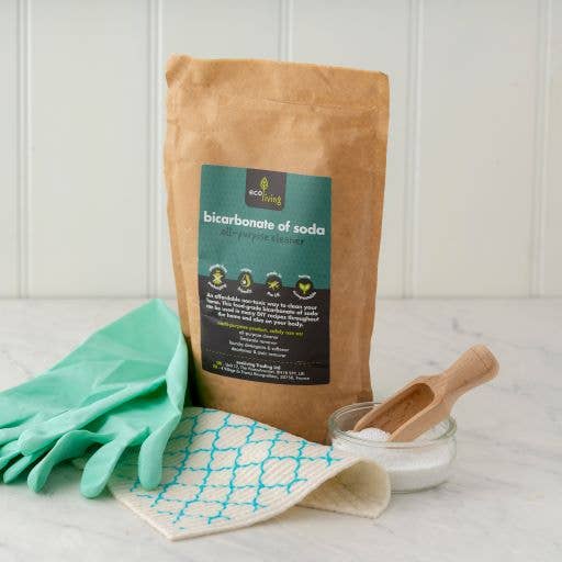 Bag of bicarbonate of soda with gloves, cloth, and scoop on a light surface