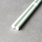 Two light green chopsticks on a gray surface