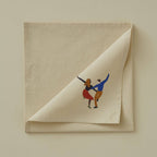 Beige folded napkin with embroidered design of a couple on a beige background
