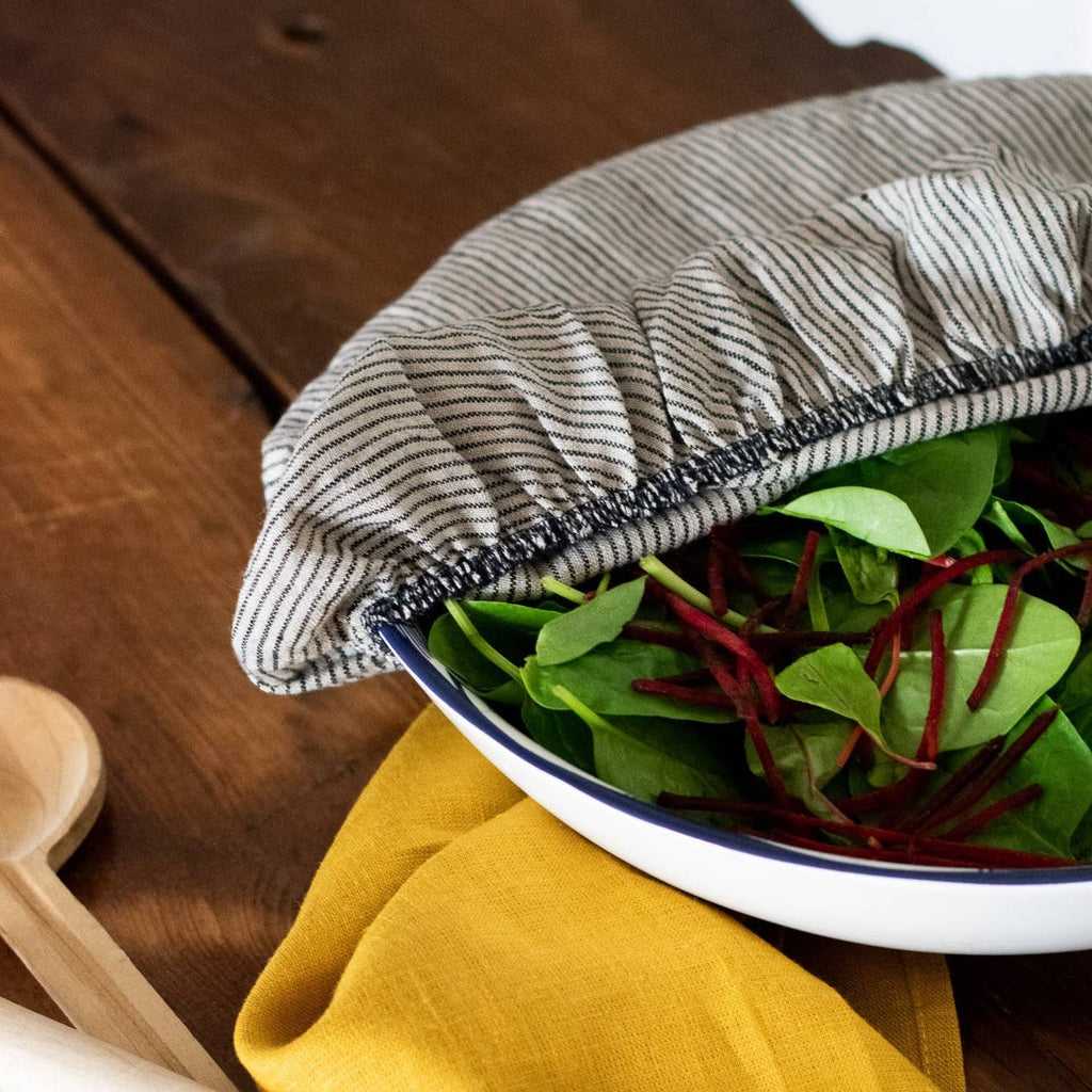 Bowl of salad with a striped cover on a wooden surface
