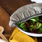 Bowl of salad with a striped cover on a wooden surface