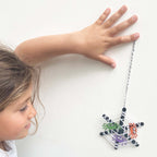 Child playing with a spider web toy on a white background