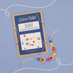 Cotton Twist rainbow bracelet kit with colorful beads on a blue background