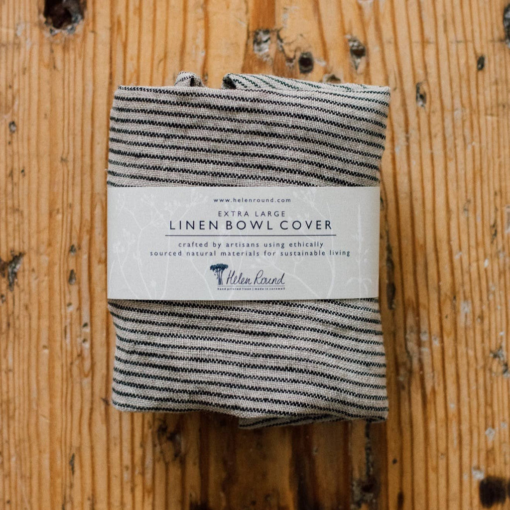 Folded black and white striped linen bowl cover with a label on a wooden surface