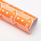 Roll of orange paper with white house pattern on a light pink background