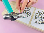 Hand using a hammer to bend metal wires on a pink background