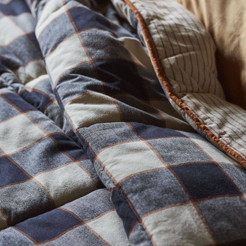 Close-up of a checkered quilt with blue, gray, and beige colors.