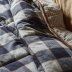 Close-up of a checkered quilt with blue, gray, and beige colors.