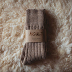 Pair of brown socks with a 'Moul't' label on a textured beige background
