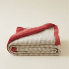 Quilted bedspread with red border and beige striped pattern 