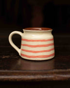 Ceramic mug with red stripes on a dark wooden surface