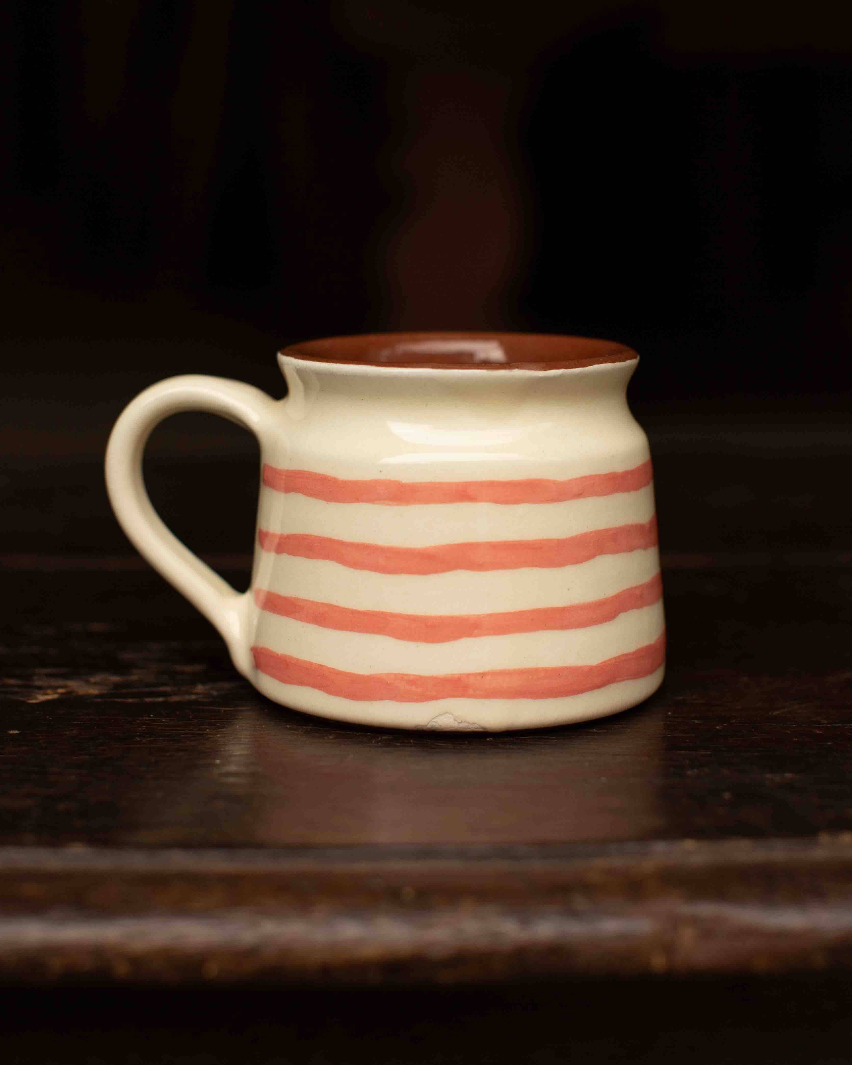 Ceramic mug with red stripes on a dark wooden surface