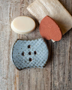 Soap bars on a wooden surface with blue speckled soap dish.