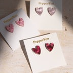 Heart-shaped earrings on 'PepperYou' branded cards on a light wooden surface