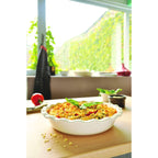 Casserole dish with a colorful dish on a table with a window in the background