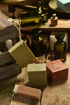 Various soaps on a wooden surface with bottles in the background