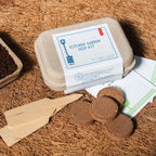 Kitchen garden seed kit with seed trays and tools on a natural brown surface