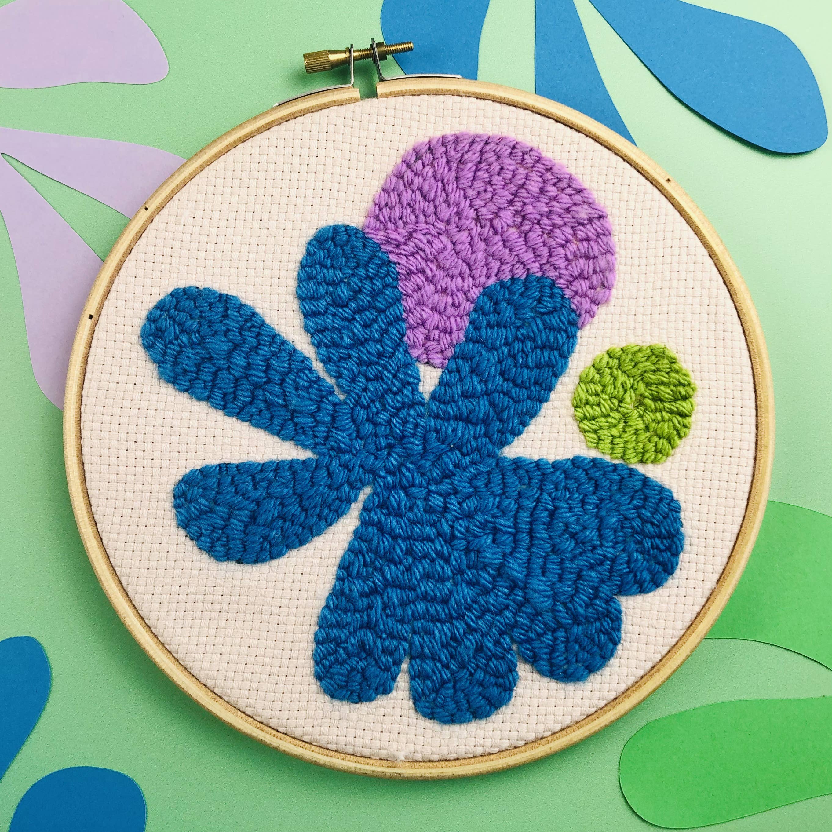 Embroidery hoop with blue and purple floral design on a colorful background
