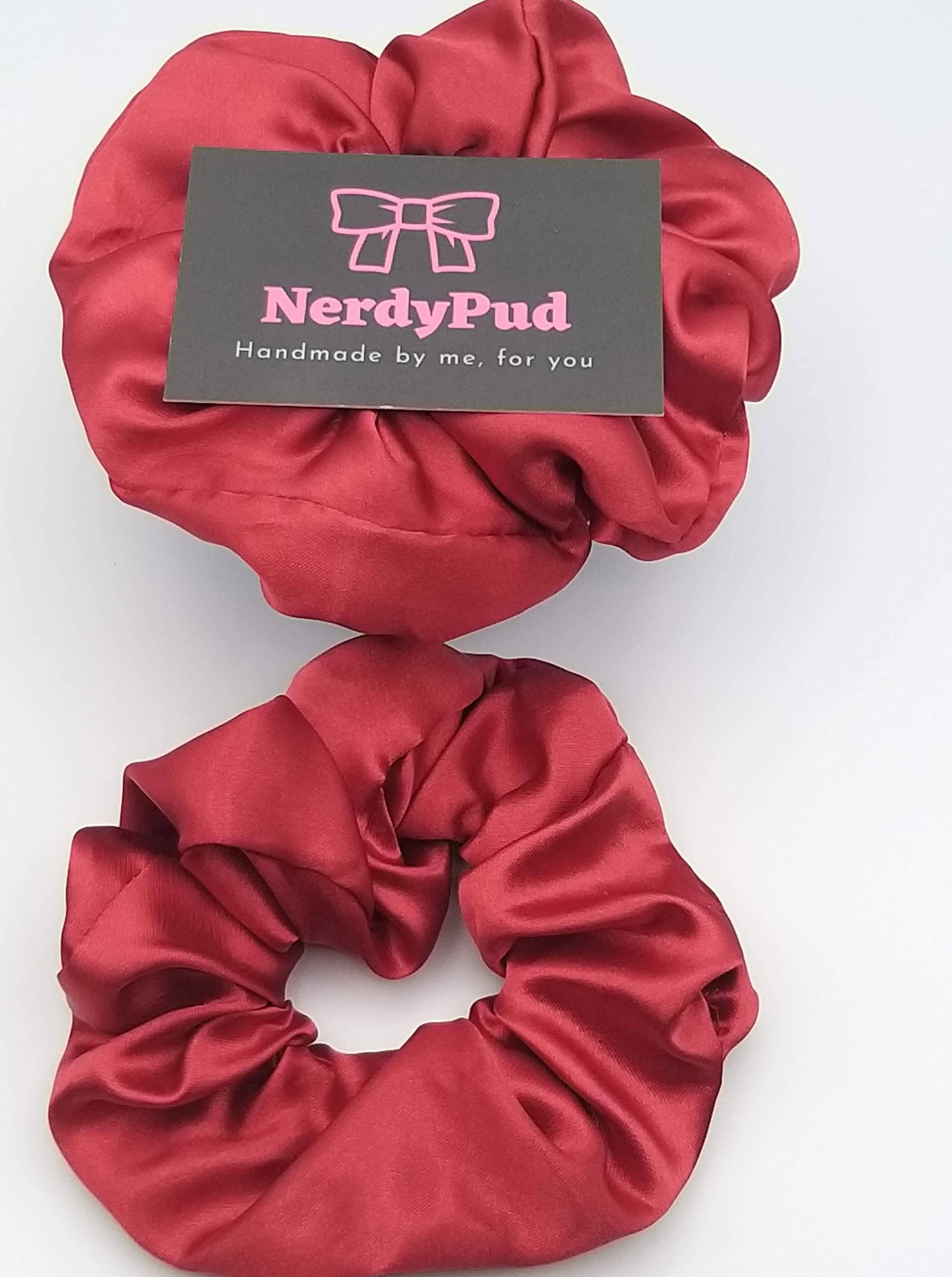 Two red satin scrunchies with a 'NerdyPud' label on a white background