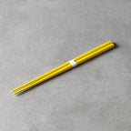 Yellow chopsticks with a white band on a gray surface