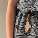 Person wearing a black and white patterned garment with a decorative pendant.