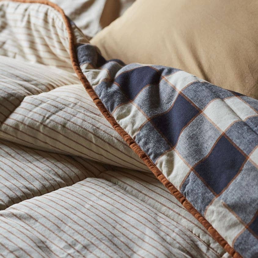 Close-up of a checkered quilt with brown border on a bed