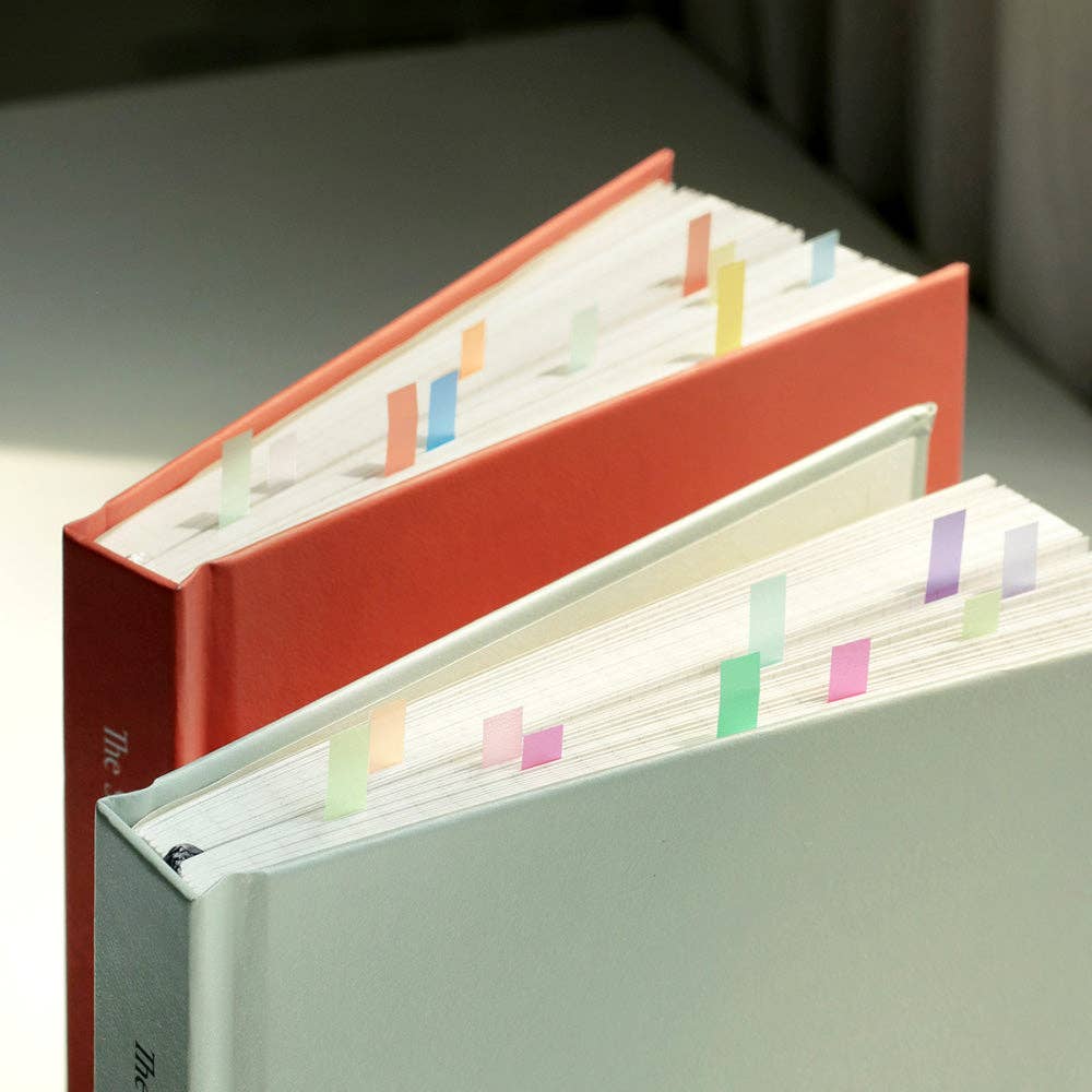 Two open books with colorful flags on a neutral background