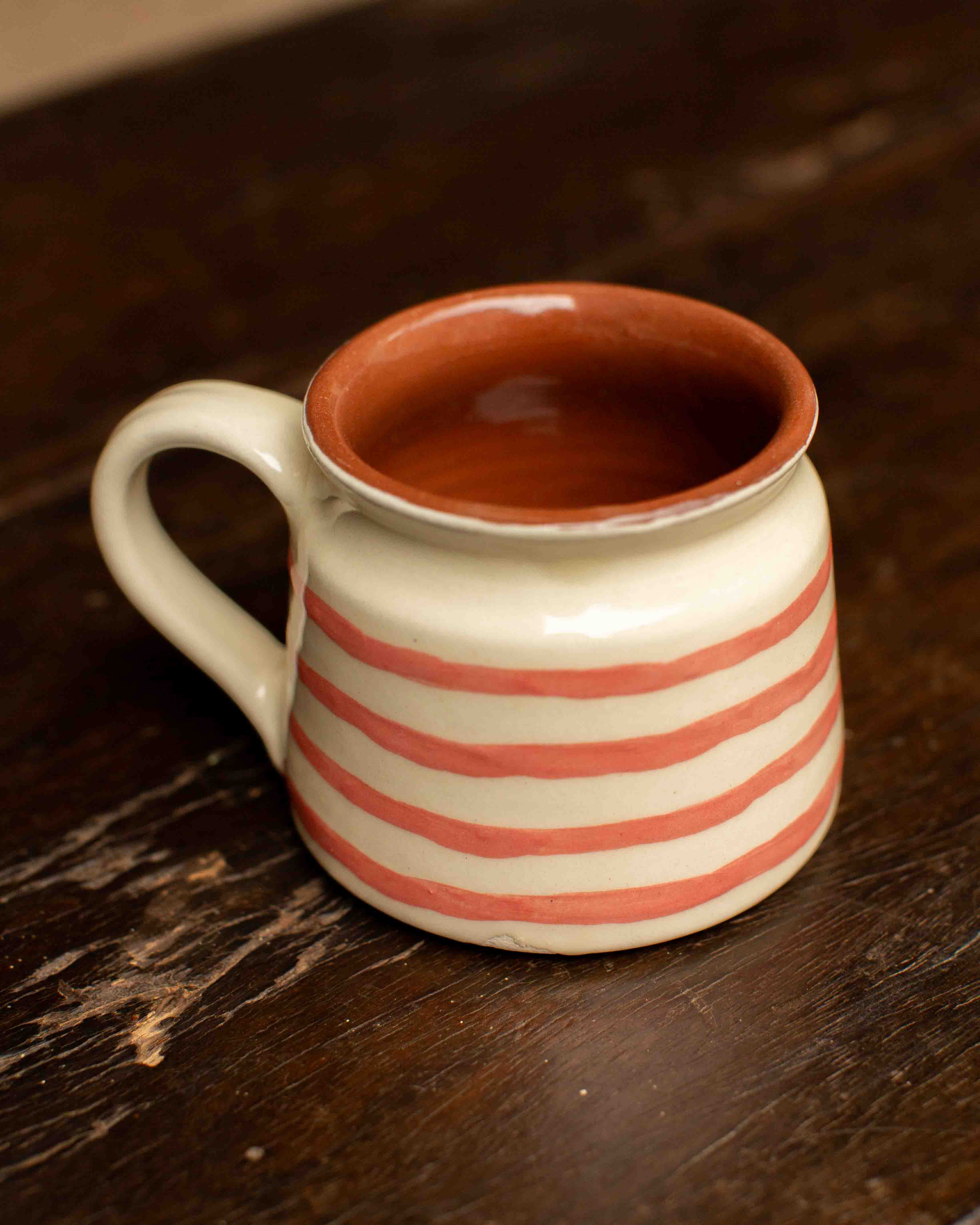 Ceramic mug with red stripes on a wooden surface