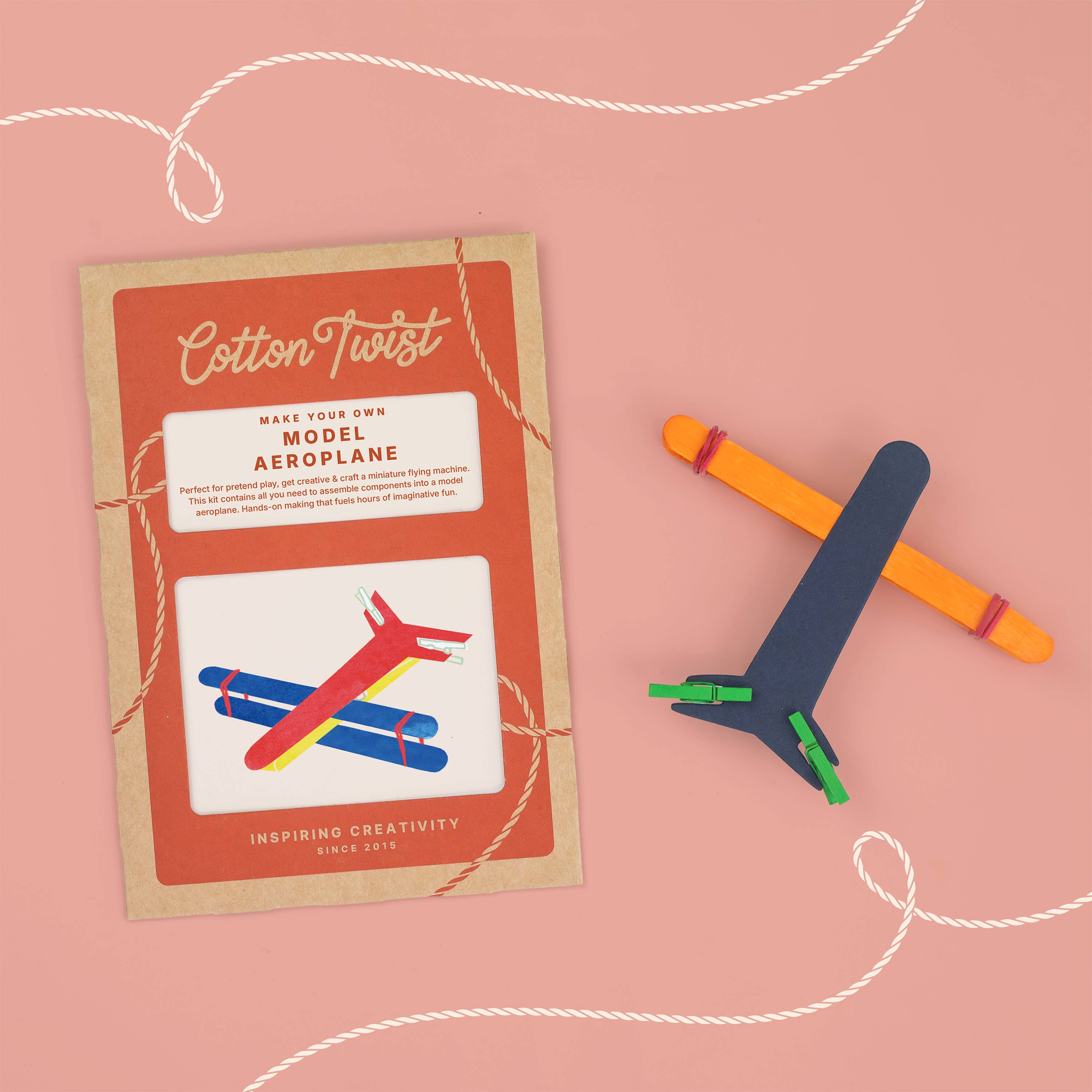 Cotton Twist model airplane kit with colorful sticks on a pink background